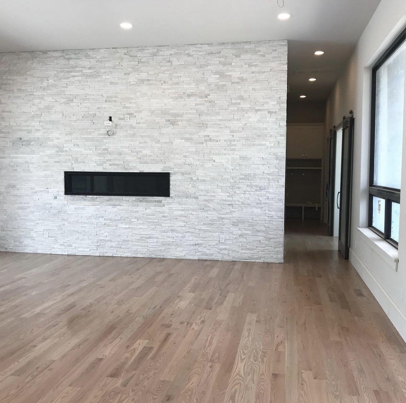 Red oak floor in a modern living room with a stone accent wall