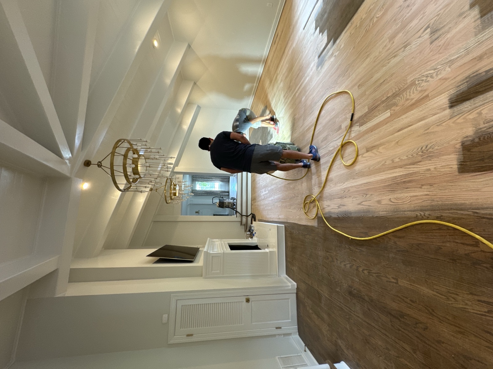 Owner Juan Silva refinishing a hardwood floor in a vaulted living room